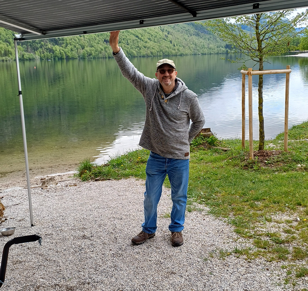 Person in a relaxed pose by the shores of Lake Bohinj, enjoying the serene atmosphere and scenic beauty.