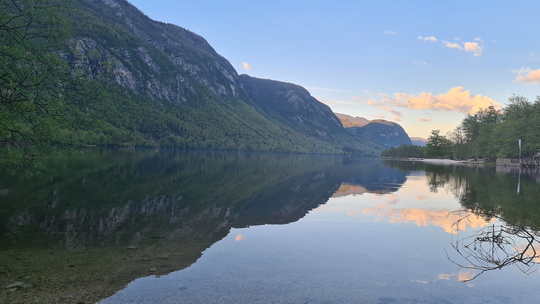 Morning view over Lake Bohinj, with mist rising from the tranquil waters and the surrounding mountains.