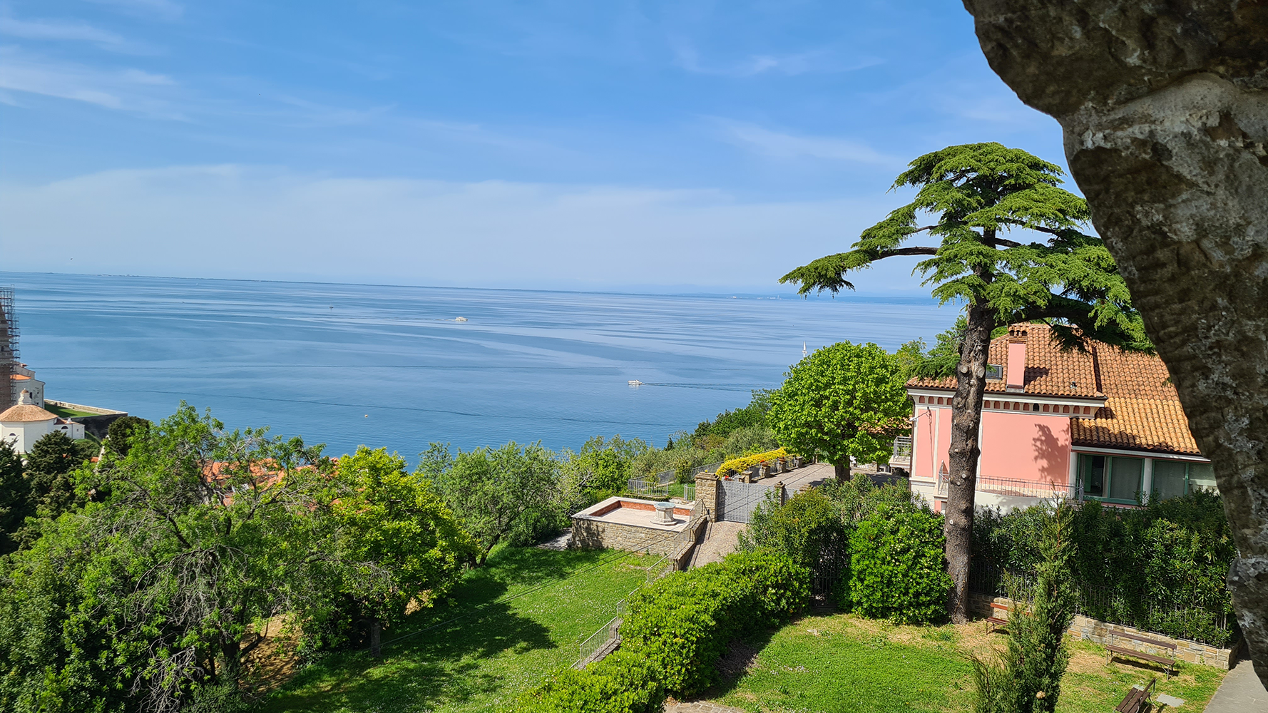View of the ancient walls of Piran overlooking the sea, with boats floating in the harbor.