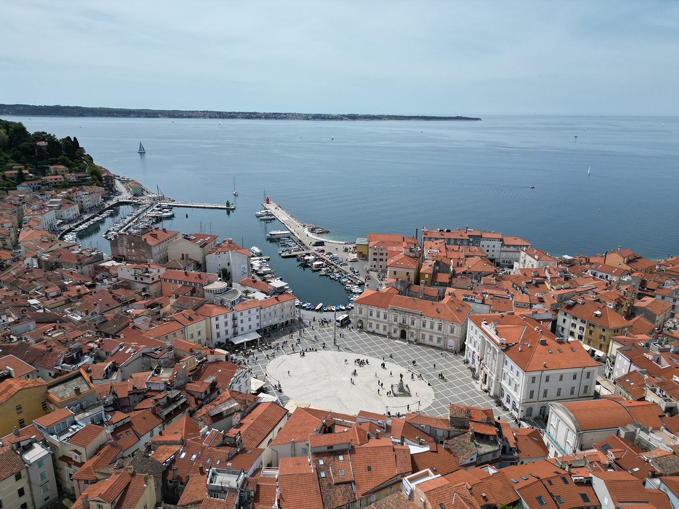Panoramic view overlooking Piran Old Town from the Piran city walls, with its charming narrow streets, orange-tiled roofs, and the Adriatic Sea in the background.