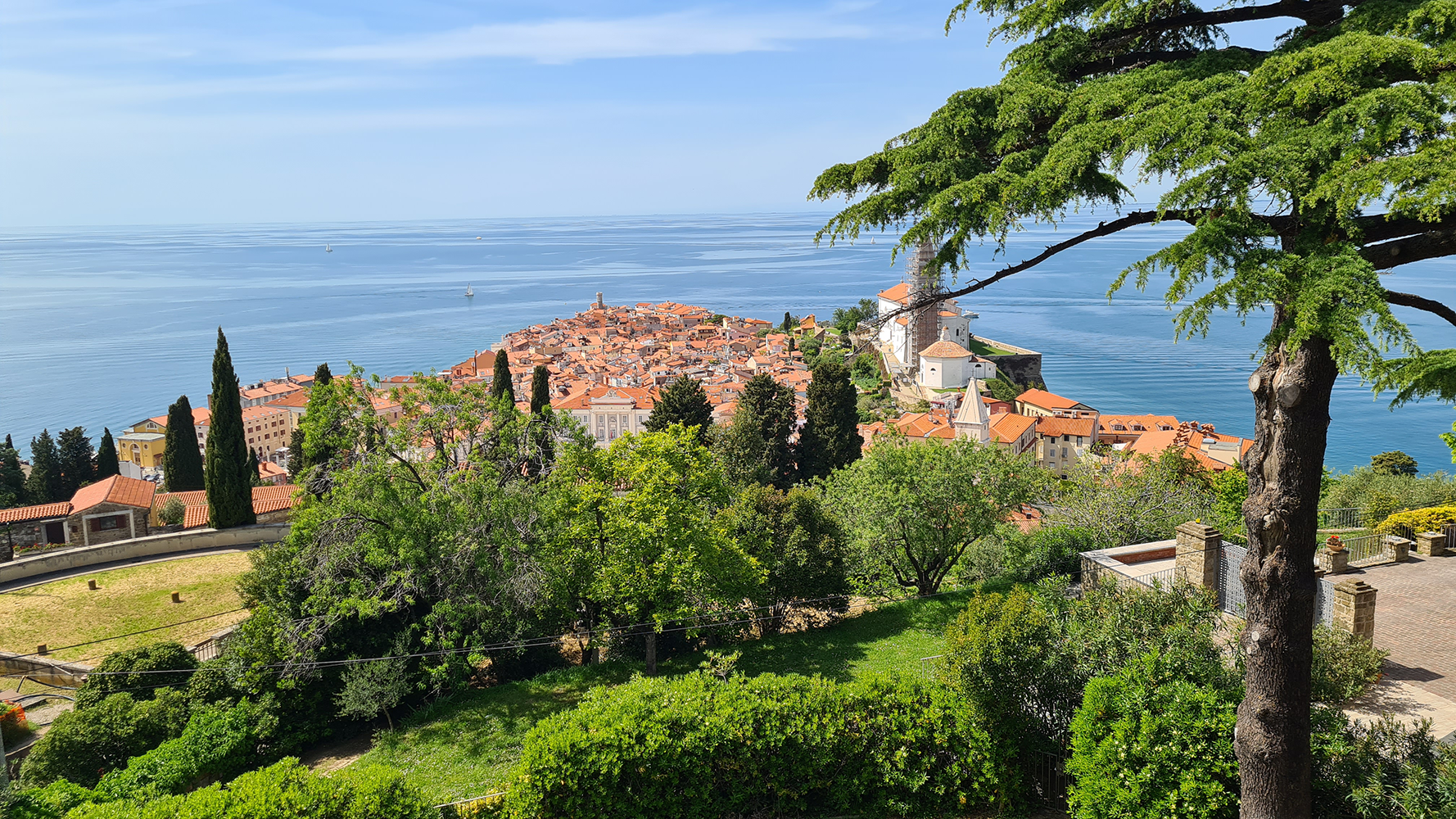 View of the ancient walls of Piran overlooking the sea, with boats floating in the harbor.