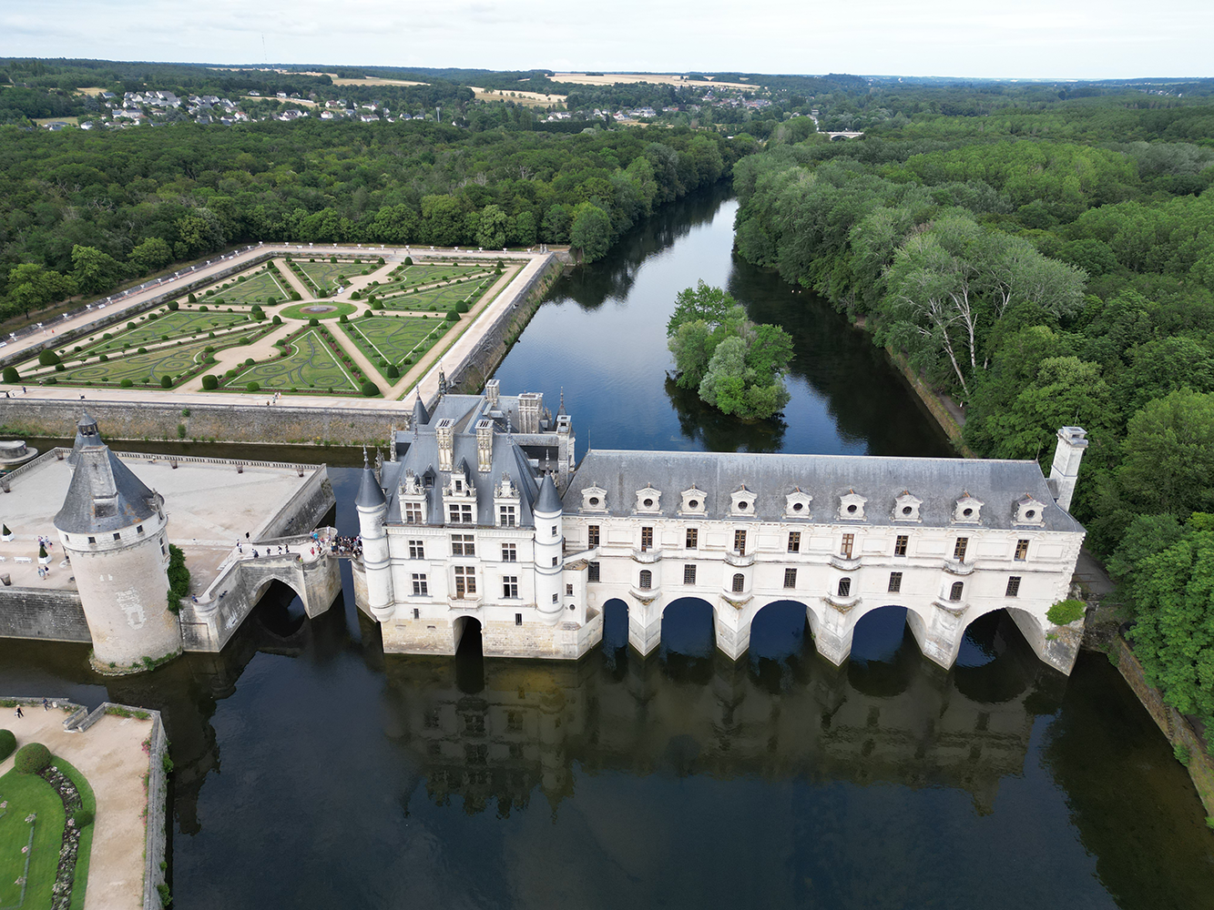 Aerial view of the gardens and river surrounding Château de Chenonceau, showcasing its scenic beauty.