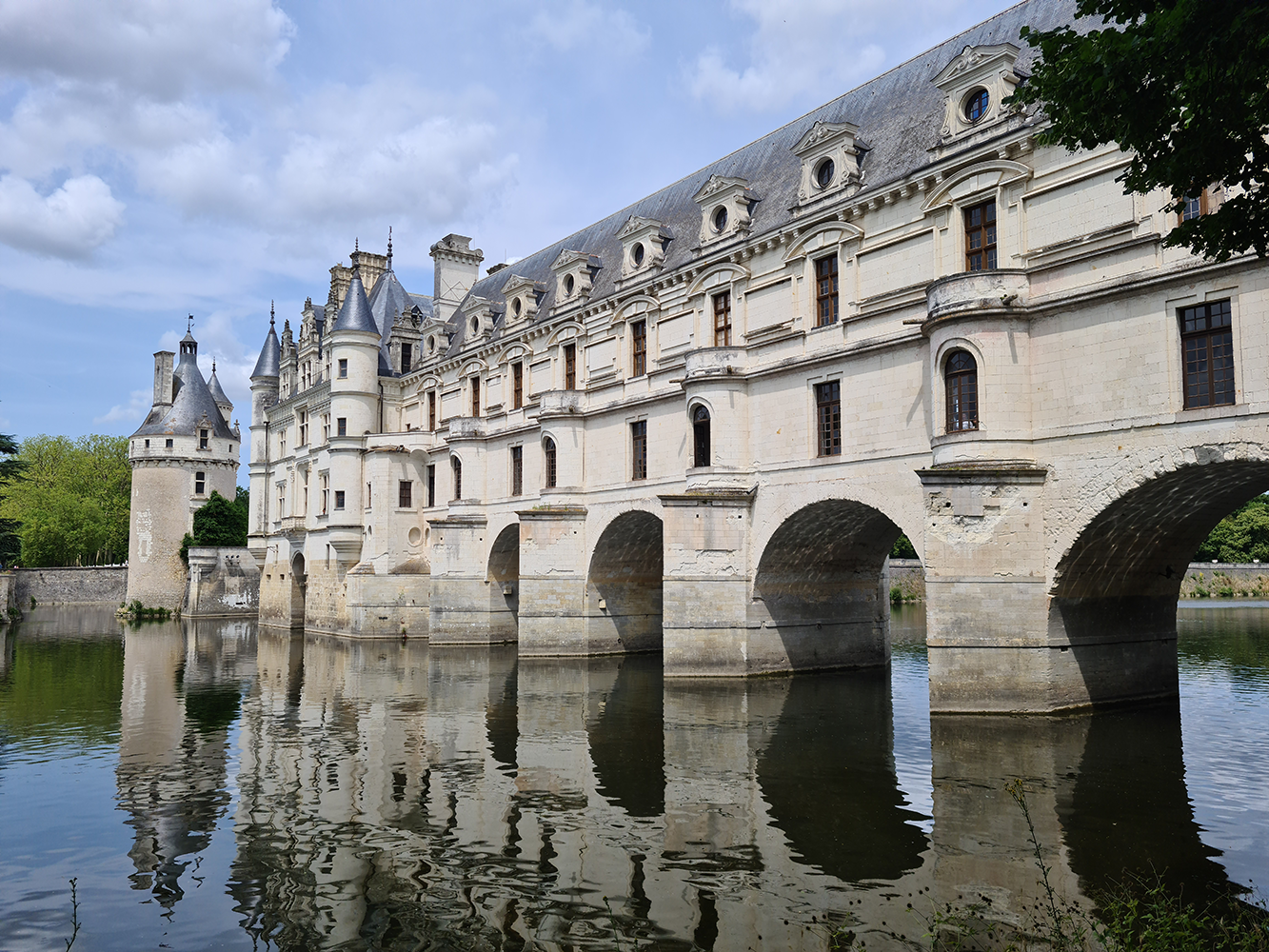 Château de Chenonceau viewed from the river, showcasing its elegant arches and scenic surroundings.