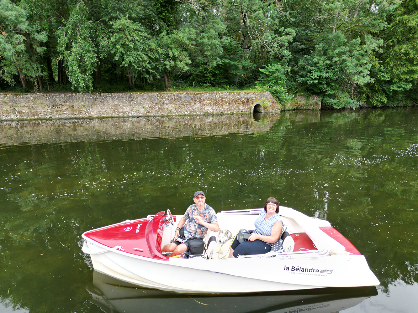 Boat sailing on the tranquil waters of the Cher River, with lush greenery framing the scene.
