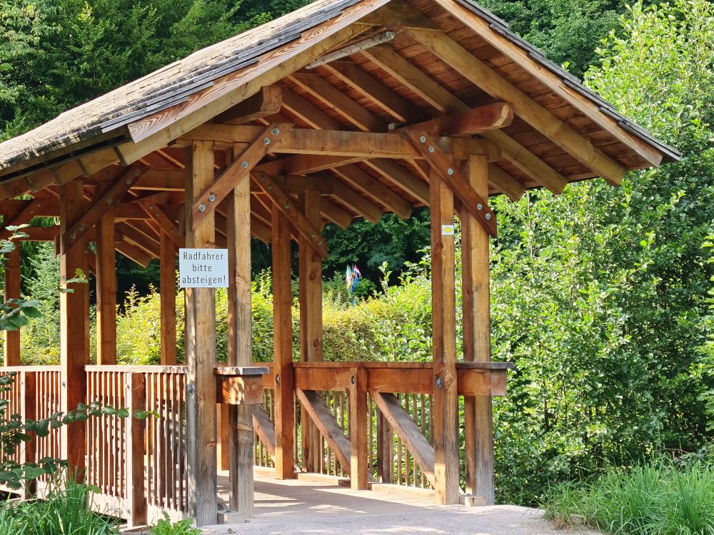 Bridge at Camping Müllerwiese leading to the fields next door, with a scenic backdrop of greenery and open fields.