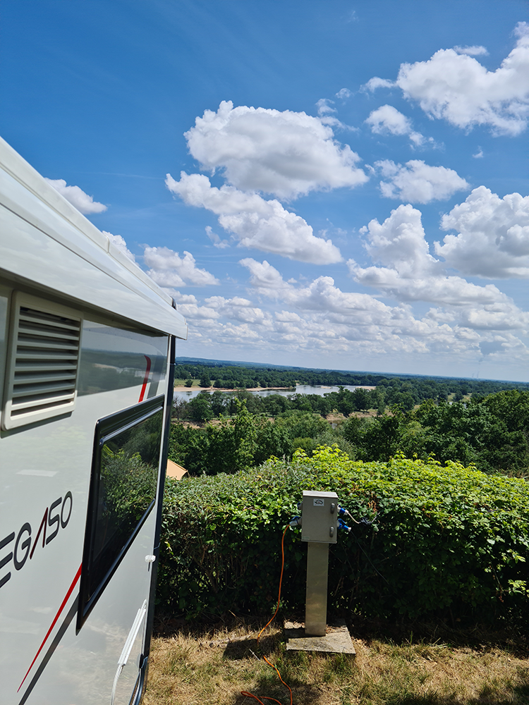 Scenic view from a motorhome at Camping Huttopia Saumur, overlooking the breathtaking Loire Valley with rolling hills and the majestic Loire River.