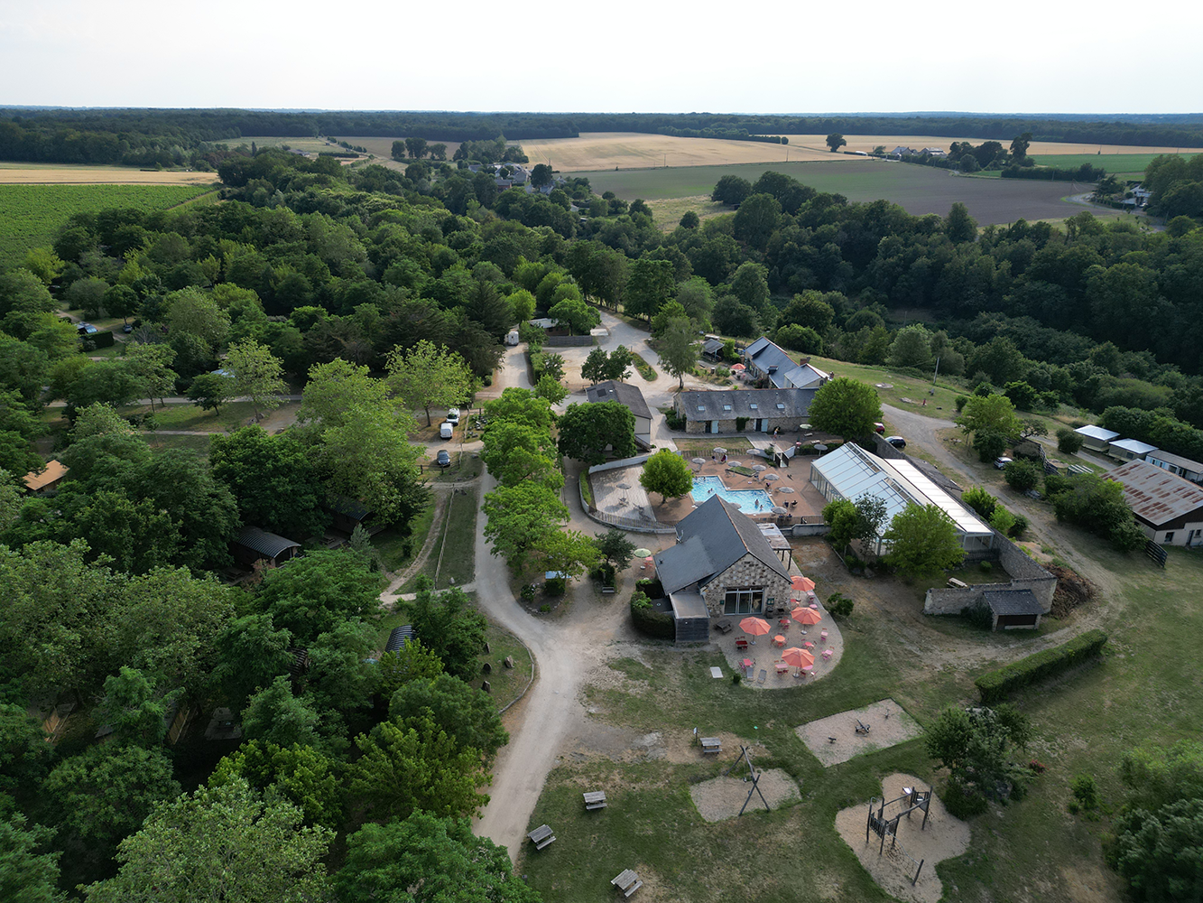Aerial view of Camping Huttopia Saumur, offering a stunning perspective of the picturesque Loire Valley with rolling hills and the meandering Loire River.
