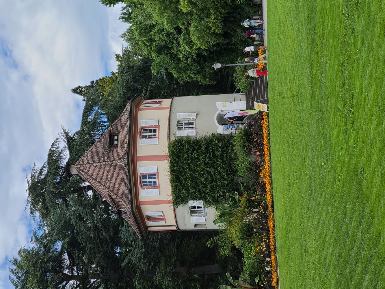 Round building in the garden on Mainau Island, surrounded by vibrant flowers and lush greenery.