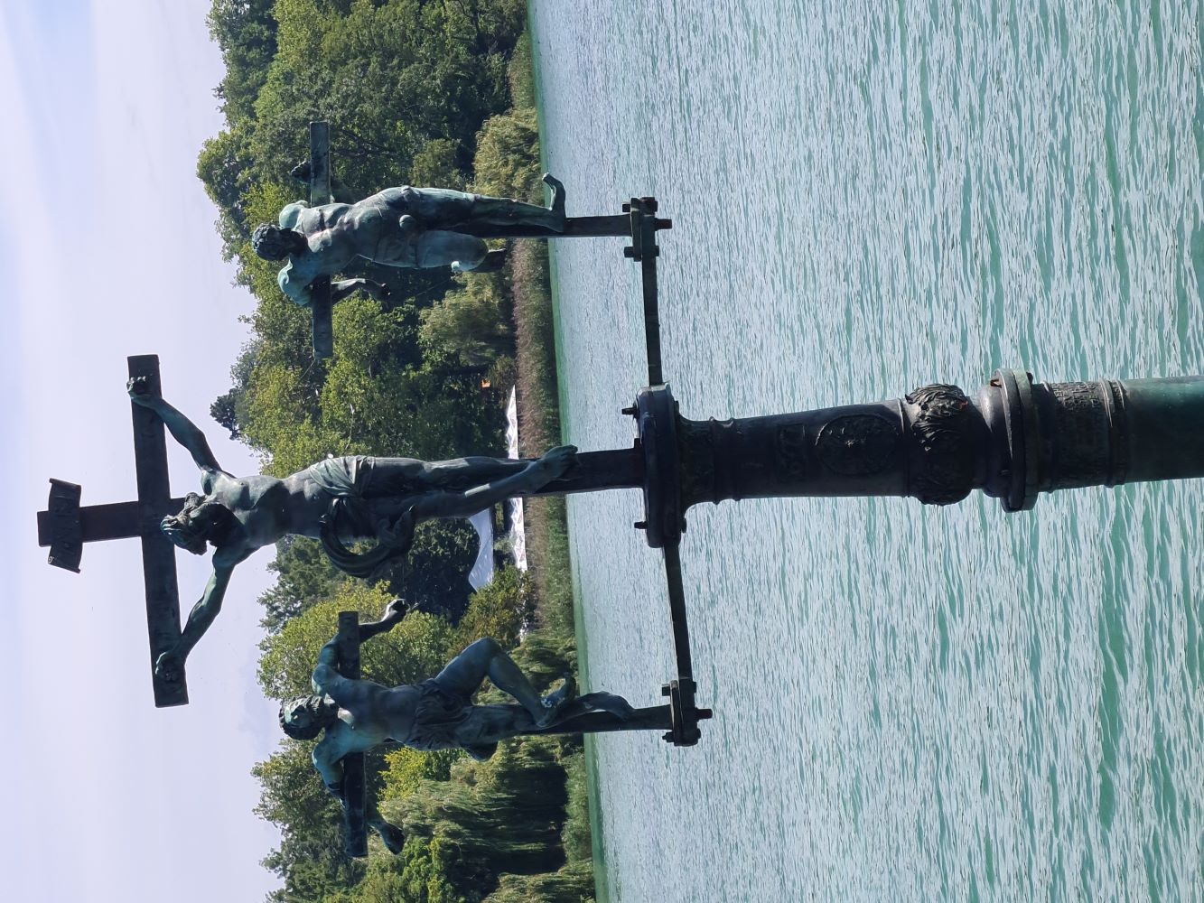 Water sculpture post on Mainau Island, surrounded by lush greenery and colorful flowers.
