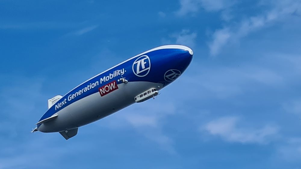 Airship flying overhead, against a clear blue sky.
