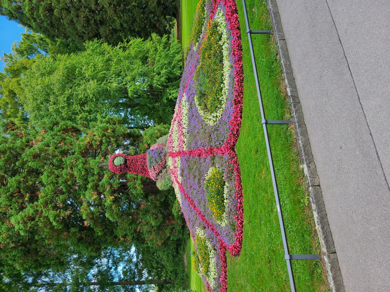 Peacock flower sculpture on Mainau Island, adorned with colorful flowers and surrounded by lush greenery