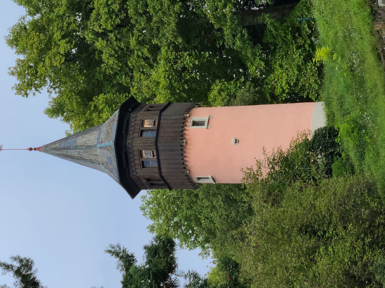 Garden tower on Mainau Island, surrounded by vibrant flowers and lush greenery, with a clear blue sky in the background.