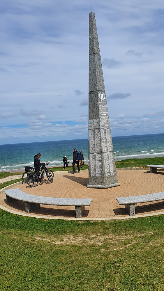 A solemn obelisk overlooking Omaha Beach at the Omaha Beach Memorial, symbolizing remembrance and honoring the sacrifices made during the D-Day landings of World War II.