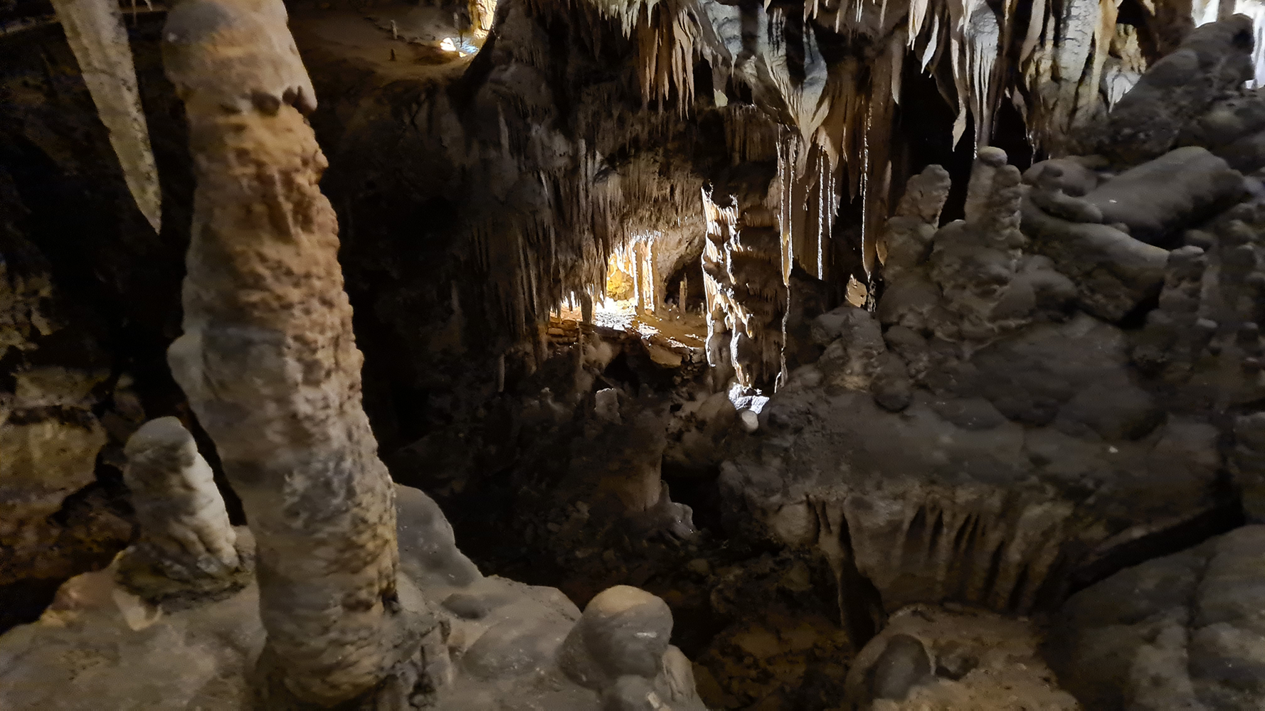 Interior of Postojna Cave, featuring stunning limestone formations illuminated by soft lighting.