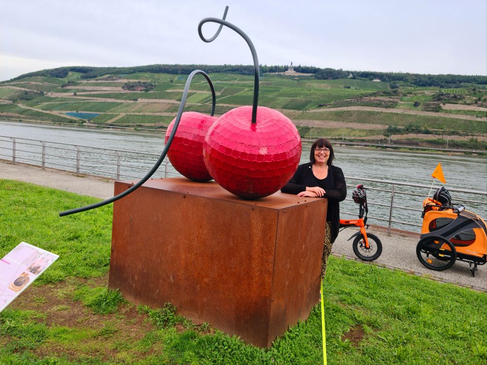 Public art installation on the Bingen Rhine Promenade, with the river and scenic landscape in the background.