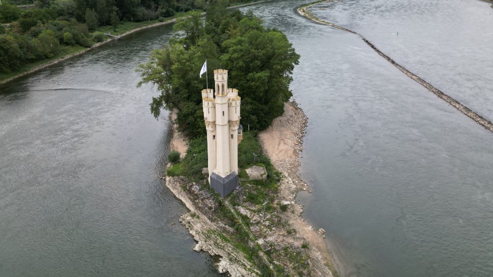Aerial view of the Mouse Tower (Mäuseturm) on an island in the Rhine River, surrounded by water and lush greenery.