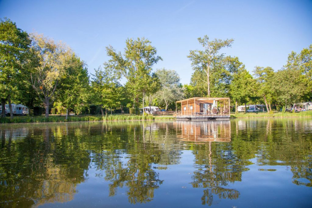 A serene view over the lake at Camping Saint Emilion, reflecting the tranquil surroundings and lush greenery.