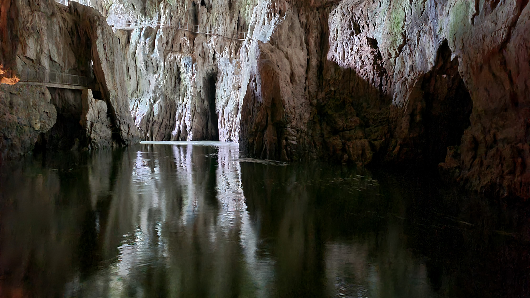 Crystal-clear pool of water inside Skocjan Caves, reflecting the majestic limestone formations.