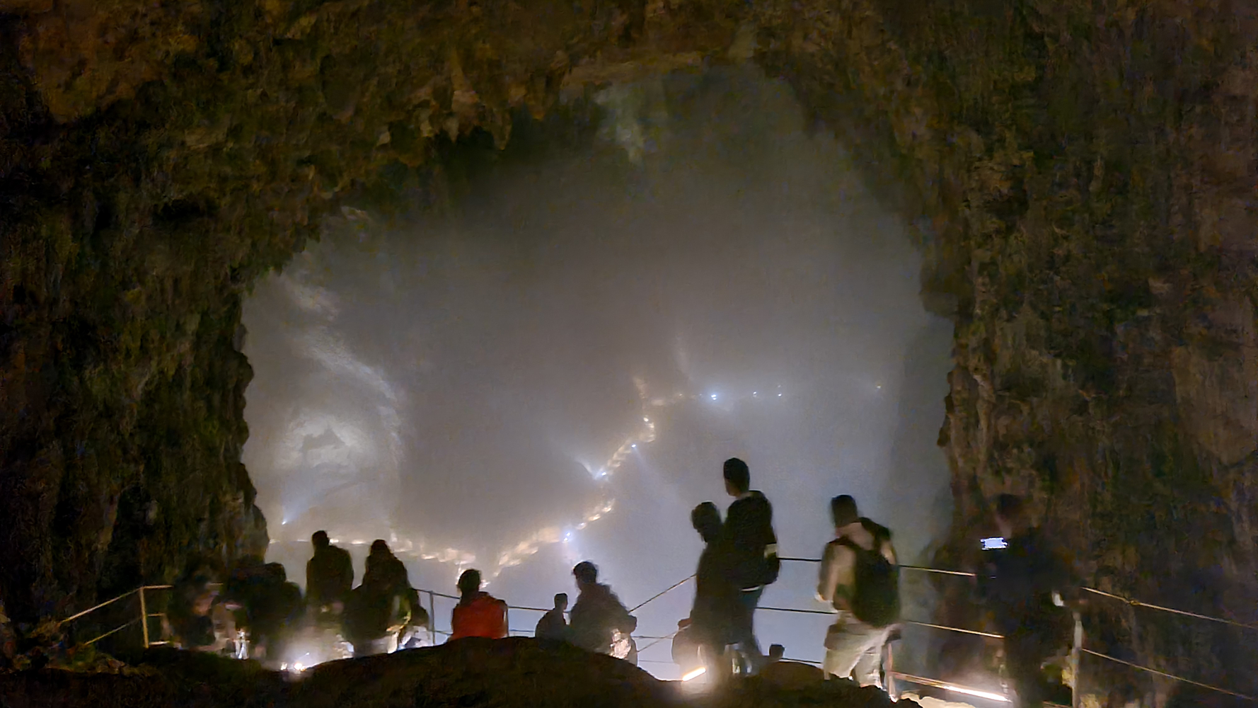Interior view of Skocjan Caves with visitors walking along the designated pathways, surrounded by magnificent limestone formations.