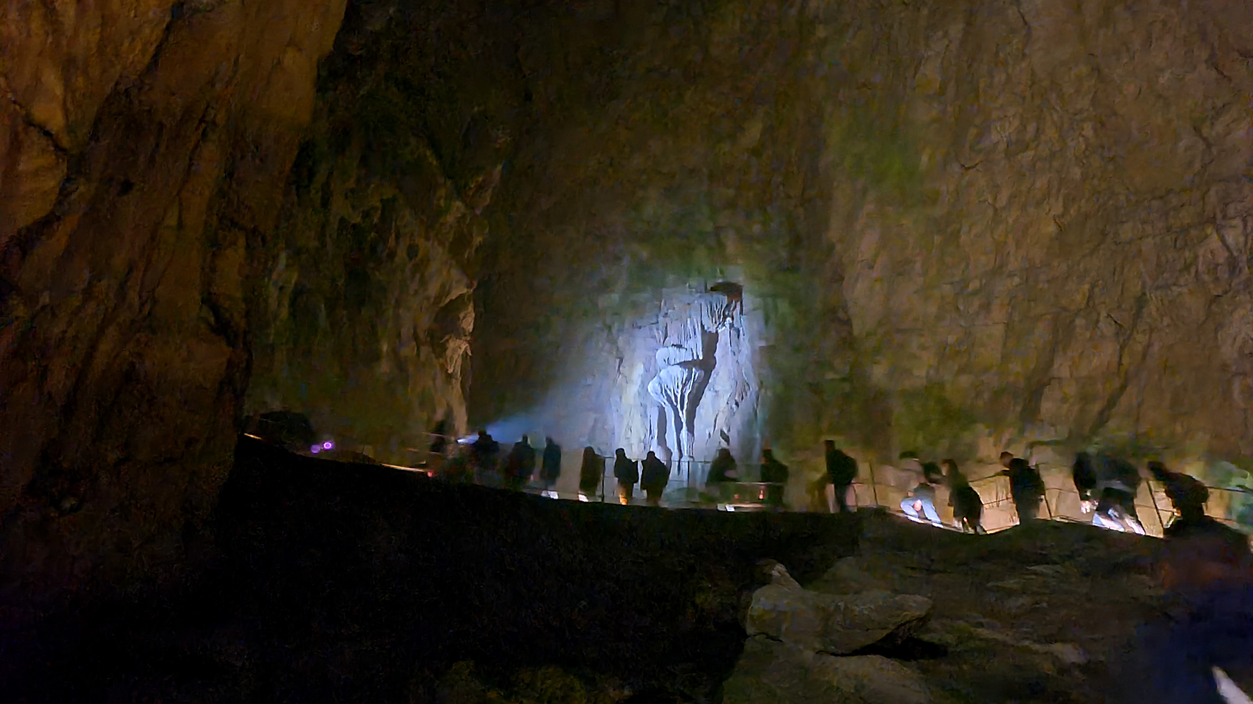 Interior view of Skocjan Caves with visitors walking along the designated pathways, surrounded by magnificent limestone formations.