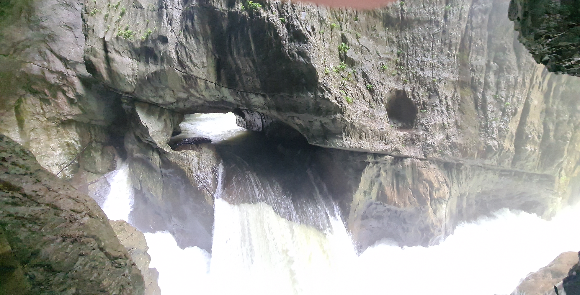 Waterfall inside Skocjan Caves, cascading down the rugged limestone formations into a crystal-clear pool.