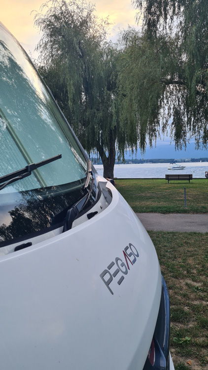 Roller team motorhome near Lake Geneva with trees and grassy shoreline near Camping Geneva-Vésenaz