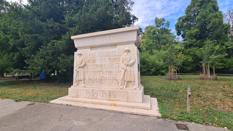 Stone monument with a statue honoring Geneva's soldiers who died between 1945 and 1959, surrounded by trees and grass