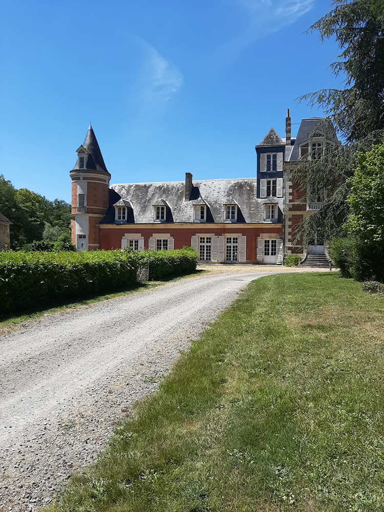 A captivating view of the approaching L'Orangerie de Beauregard, surrounded by lush greenery and blooming flowers.