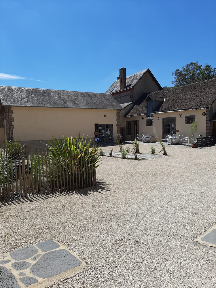 The serene courtyard of L'Orangerie de Beauregard, adorned with lush greenery and bathed in soft sunlight.
