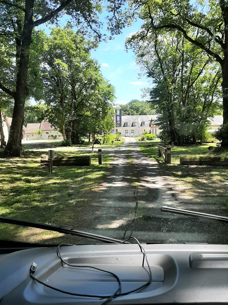 A captivating view of the approaching L'Orangerie de Beauregard, surrounded by lush greenery and blooming flowers.